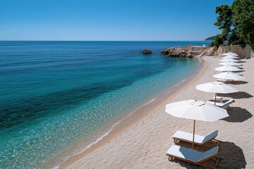 Obraz premium A beautiful beachfront view features elegant loungers resting under umbrellas, surrounded by lush greenery, with the tranquil sea inviting visitors to unwind and relax.