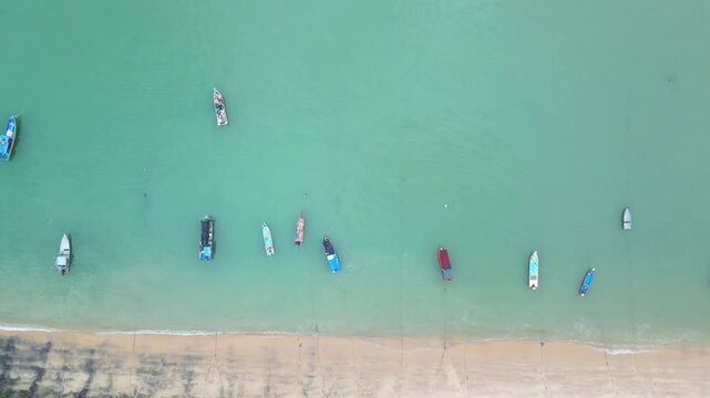 Aerial view of malay traditional fishing boats in turquoise water by the beach.