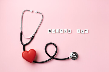 Red heart with doctor stethoscope and the inscription Nurses Day on pink background. Top view.