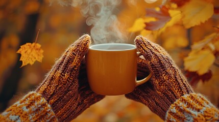 Hands holding a mug of hot beverage in autumn season