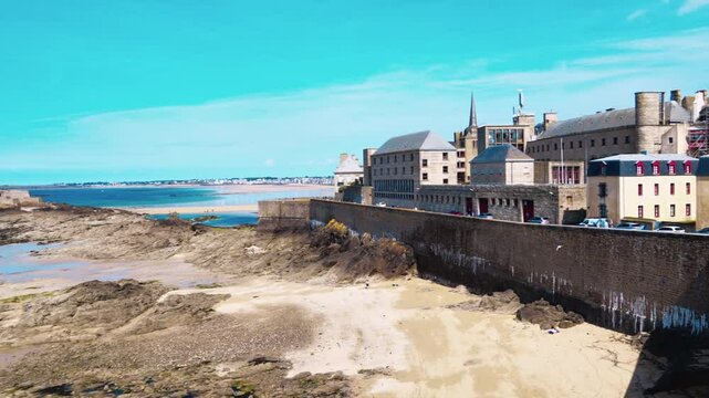 Skyline of the English Channel coast from fortress walls of the city of Saint-Malo during the ocean low tide against a blue sky. View of the old fortress National Fort. La Manche, Brittany reg. France