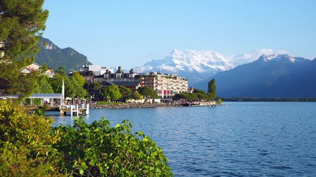 Beautiful summer evening panorama of Lake Geneva with picturesque shores against Alpine mountains in the rays of the setting sun in Montreux, Switzerland. 4K video