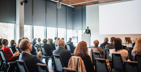 Speaker giving a talk in conference hall at business event. Rear view of unrecognizable people in...