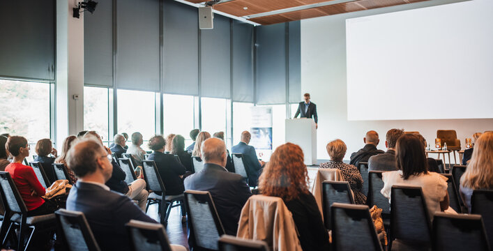 Speaker giving a talk in conference hall at business event. Rear view of unrecognizable people in audience at the conference hall. Business and entrepreneurship concept