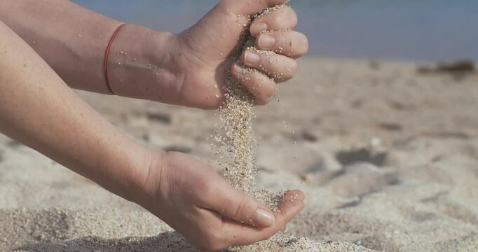 Sand falling from hand in slow motion on a beach. Vacation and travel concept. Shot on super slow motion camera 1000 fps.
