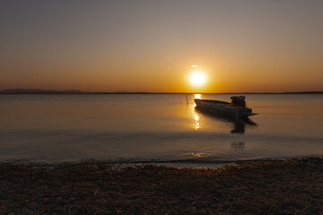 Pa Sak Jolasid Dam, Serene Coastal Sunset: A tranquil view of an island at dusk, with a silhouette of hills and serene water reflecting the warm colors of the setting sun, creating a peaceful
