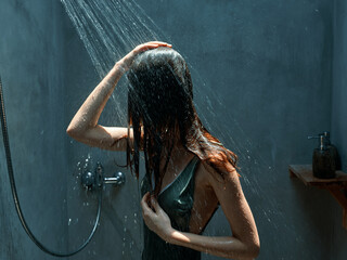 Refreshing shower in a modern bathroom woman standing under streaming water with eyes closed and water running down her back