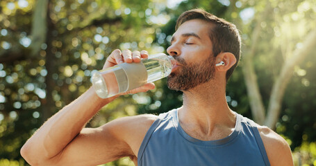 Man, fitness and drinking water in park, break and earphones with streaming subscription in summer. Person, bottle and liquid for hydration, detox and wellness with exercise, workout and training