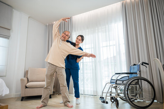 Old senior man enjoys training with physiotherapist for outstretched arms at home, Asian physical therapist patient nursing helping elderly exercising arm stretch, Rehabilitation of disabled concept - Powered by Adobe