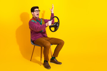 Fototapeta premium Young man with glasses and colorful sweater portraying an excited expression on a bright yellow background