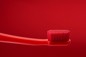 Red toothbrush without paste on a red background. Oral hygiene of the mouth. Dentist.