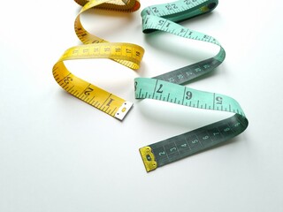Two twisted colored measuring tapes on white background
