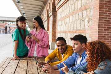 Group of young students using mobile phones and enjoying together outdoors