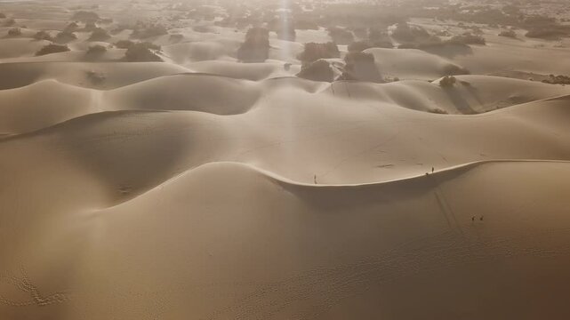 Flight over of people walking on Maspalomas sand dunes at sunset, Gran Canaria, Canary islands, Spain