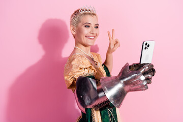 Smiling woman in a royal dress and armor taking a self-portrait against a pink background