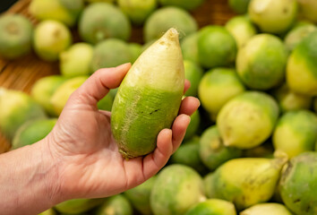Hands of buyer taking green radish root vegetable from counter in a supermarket close-up.