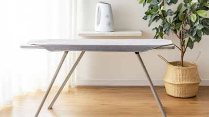 A modern ironing board sits in a sunlit room with a kettle and a potted plant, showcasing a clean and minimalistic design.