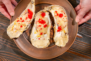 Serving baked oysters with cheese on table close-up top view.