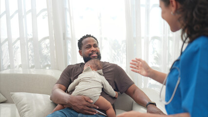 Fototapeta premium A doctor uses a stethoscope to check on the health of a little boy as he sleeps in his father's arms