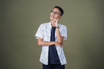 Asian man with glasses wearing white casual shirt posing thinking, dizzy or looking for ideas....