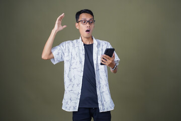 Young Asian man with casual glasses surprised expression getting surprise while pointing to...