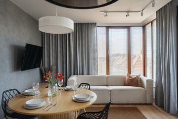 Modern cozy living room with dining area and large windows for natural light