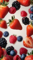 Berry Mix in Motion &ndash; Strawberries, Blueberries, Raspberries and Blackberries on Light Background, Healthy Food Concept