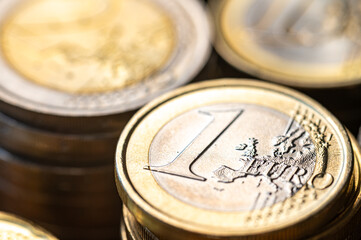 Stacks of coins next to each other, and banknotes, on white surface. Amount of money, currency and wealth.

