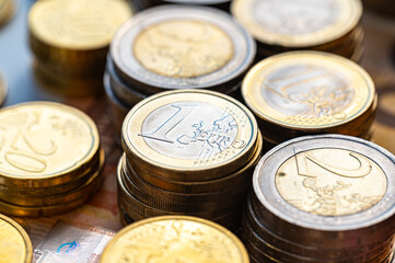 Stacks of coins next to each other, and banknotes, on white surface. Amount of money, currency and wealth.
