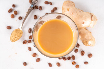 Fresh brewed ginger coffee latte cup. Creamy hot drink with ginger powder and ginger root, on white background. Healthy hot beverage. alternative medicine, remedy 