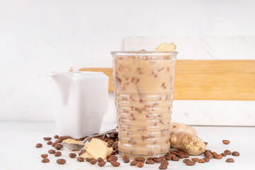 Cold brewed ginger coffee latte cup. Creamy iced drink with ginger powder and ginger root, on white background. Healthy hot beverage. alternative medicine, remedy 