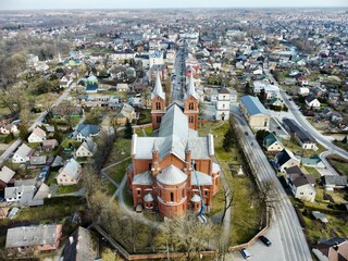 Church of St. John the Baptist, Plunge, Lithuania. Red brick church showcases Gothic Revival architecture with tall spires and pointed arches. 