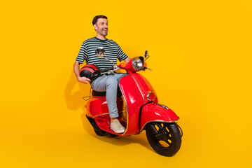 Stylish young man riding a bright red scooter against a vibrant yellow background, showcasing...