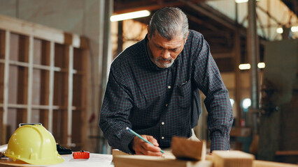 Industry, woodwork and writing with carpenter man in workshop for manufacturing or production. Carpentry, construction and planning with mature contractor in factory for professional renovation