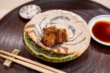 Lightly smoked conger eel sashimi served on a ceramic plate with a side of soy sauce (Japanese cuisine)