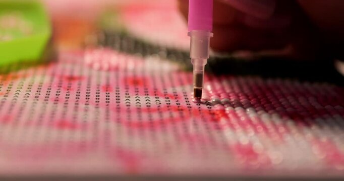 Diamond mosaic painting. A girl creates a work of art by laying out a mosaic on a canvas.