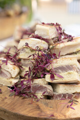 A gourmet sandwich platter featuring artisan bread, fresh tuna, and delicate microgreens, beautifully arranged on a rustic wooden board. Ideal for high-end catering, weddings, and fine dining events.