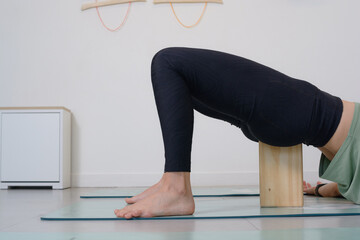 Close-up of female legs of woman practicing yoga poses with wooden blocks
