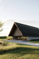 Obraz premium Contemporary architecture blends with nature in a serene landscape featuring a modern house with a triangular roof and expansive glass windows at sunrise