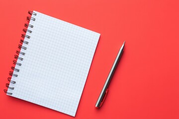 A spiral notebook and pen rest on a vibrant red background