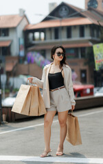 A beautiful woman joyfully shops in a lively mall, carrying multiple bags and enjoying the vibrant atmosphere of colorful stores and bright lights.