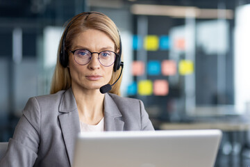 Portrait of serious confident woman with headset. Close-up businesswoman in business suit looking...