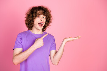 Young man in casual purple shirt with enthusiastic expression pointing at his hand, vibrant pink...