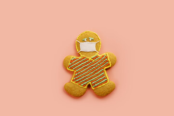 Cookie in the form of a man in a protective mask on a pink background
