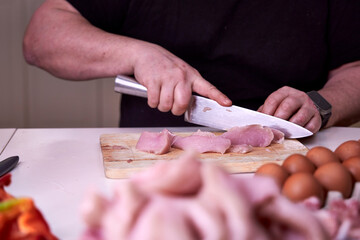 man carves turkey thigh on a wooden board close-up