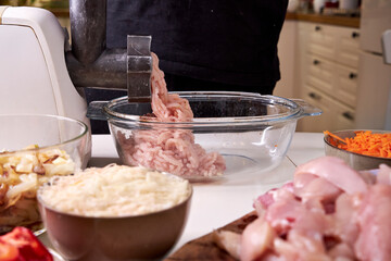 a man chops meat and vegetables in an electric meat grinder to make mincemeat for cutlets