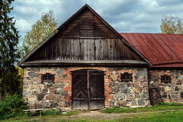 Old barn built of stones and bricks, with large wooden gates and small windows.