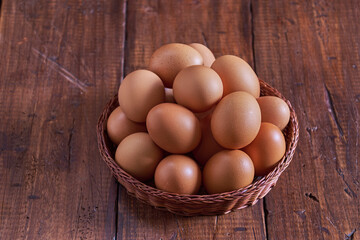 Raw brown eggs arranged in a basket with a rustic wooden background
