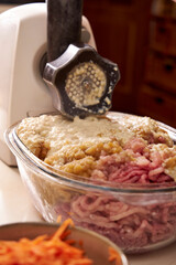 a man chops meat and vegetables in an electric meat grinder to make mincemeat for cutlets