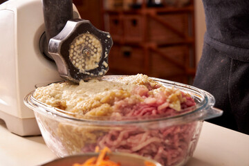 a man chops meat and vegetables in an electric meat grinder to make mincemeat for cutlets